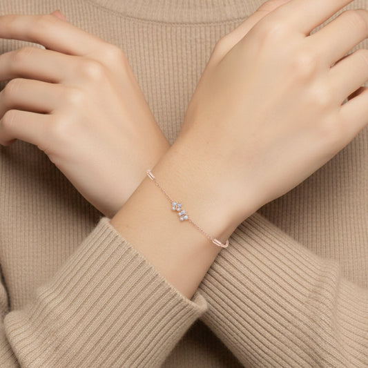 Close-up of a person wearing a delicate bracelet on a beige sweater.