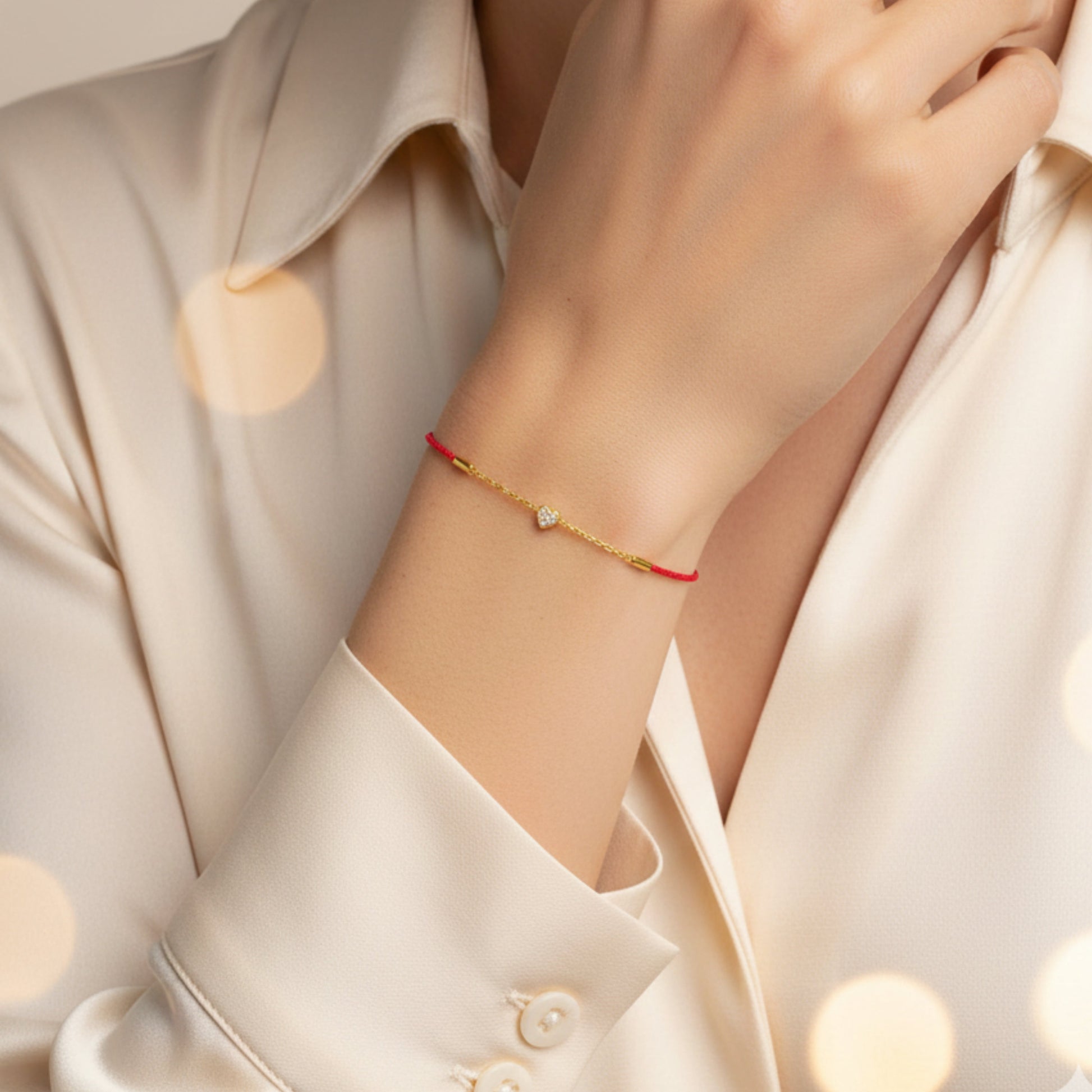 Gold bracelet with a red string worn on a wrist against a light background. Heart_silk_cord_gold_bracelet_perfect_for_gifting