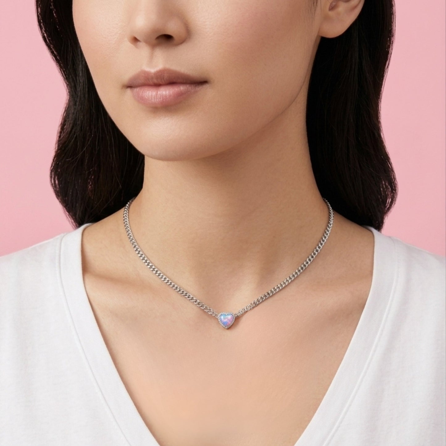 Woman wearing a necklace with a pink gemstone against a pink background