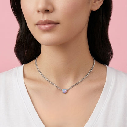 Woman wearing a necklace with a pink gemstone against a pink background