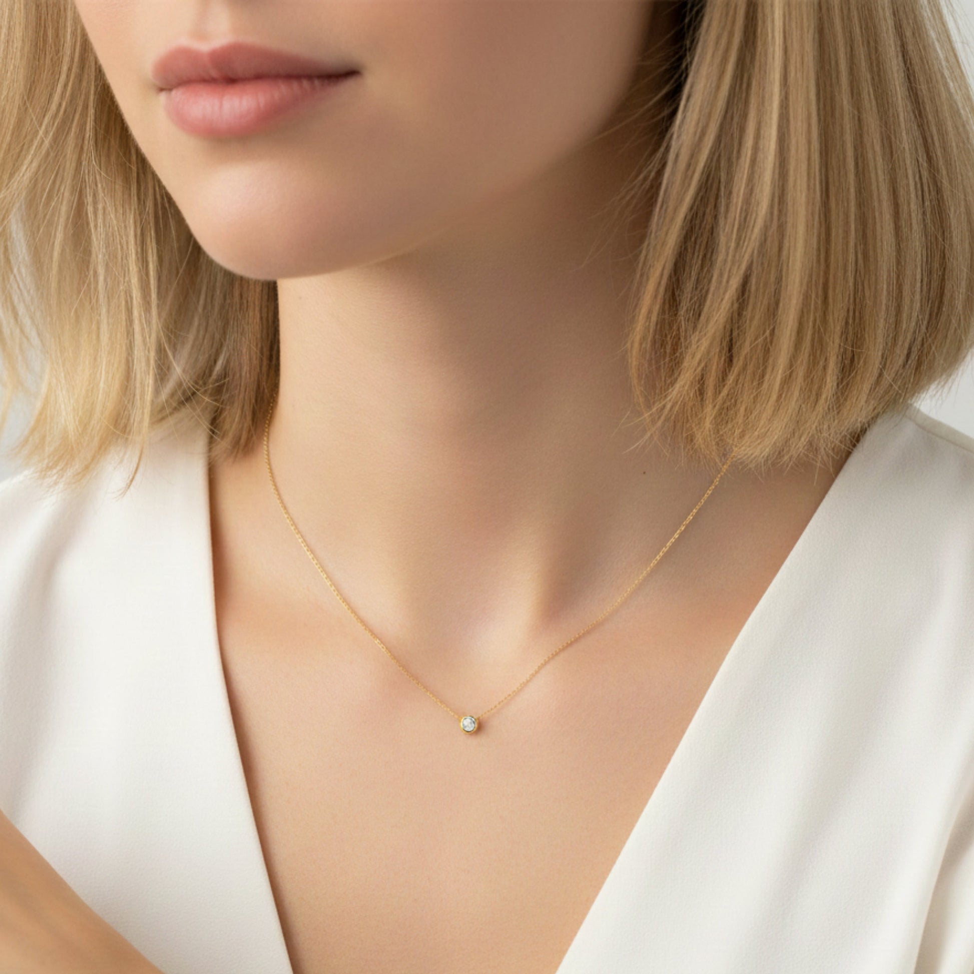 Close-up of a person wearing a gold necklace with a small pendant.