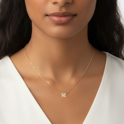 Close-up of a woman wearing a gold necklace with a butterfly pendant. 9mm butterfly pendant necklace by BLOOMTINE, crafted in tarnish-resistant gold over sterling silver with sustainable moissanite stones. Featuring an adjustable 14.5 to 16.5-inch chain for a bespoke fit, this dainty gold necklace is an ethical diamond alternative for meaningful gifting