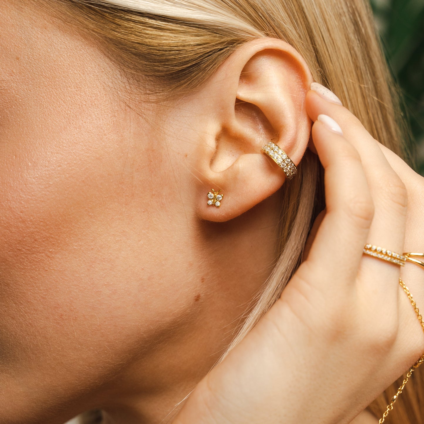 Close-up of a model's ear wearing the BLOOMTINE Enchanting Flutterfly™ Stud Earrings in 18k Gold Vermeil. The delicate butterfly design, set with light-catching lab moissanites, symbolizes a 'Spirit of Transformation' while providing an extraordinary, everyday sparkle