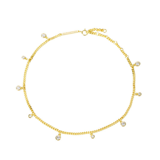 A close-up shot of the Illuminess™ Apah Water Goddess Anklet in premium gold vermeil, modeled on an olive-toned ankle. The dainty silver chain features shimmering lab-diamond droplets that catch the light, creating a liquid-sparkle effect