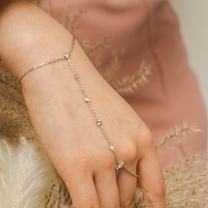 Hand wearing a delicate gold bracelet with a soft blurred background. The BLOOMTINE Illuminess™ Diamond Hand Chain in White Rhodium-plated Sterling Silver. Featuring 6 brilliant lab-grown diamonds and a diamond-cut cable chain, this celebrity-favorite 'hand harness' provides a continuous, elegant shimmer for the extraordinary human