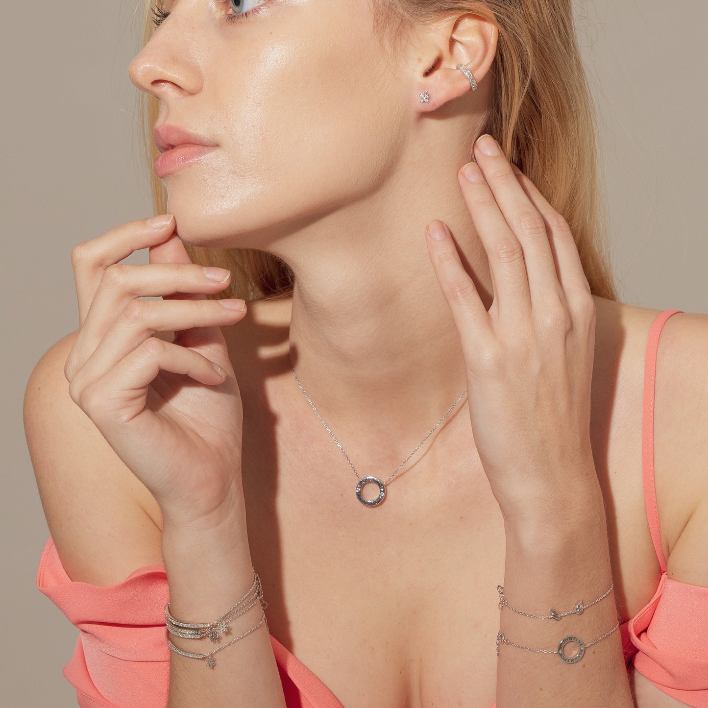 Woman wearing a necklace, earrings, and bracelets on a neutral background. A detailed-close-up of the-Illuminess-bar-bracelet, showcasing the-meticulous-setting of 21-premium-VVS-diamonds. This-shot-emphasizes the-unmatched-brilliance of the-sustainable-lab-diamonds and the-superior-craftsmanship of the-solid-14K-rose-gold. Perfect-for-customers seeking-conflict-free-diamond-jewellery with an-elite-level of clarity.